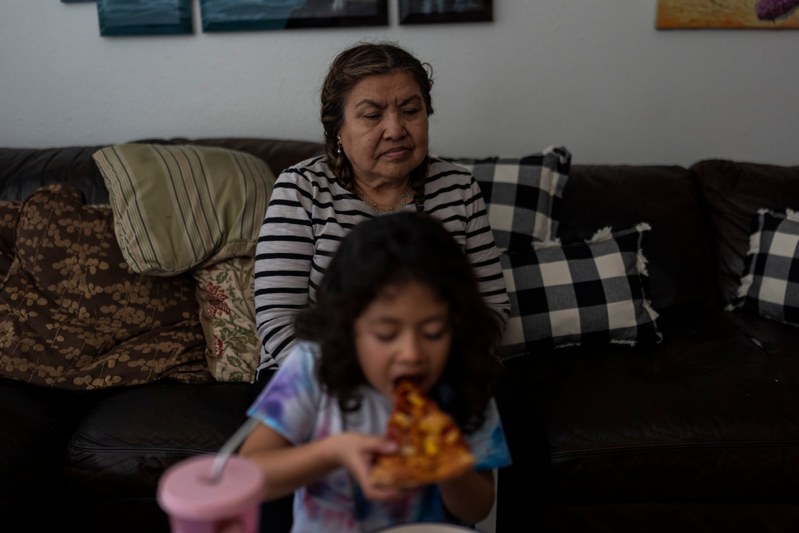 Marina Maalouf, a longtime resident of Hillside Villa, sits on a sofa as her granddaughter eats pizza for lunch in their apartment in Los Angeles, Tuesday, Oct. 1, 2024. (AP Photo/Jae C. Hong)