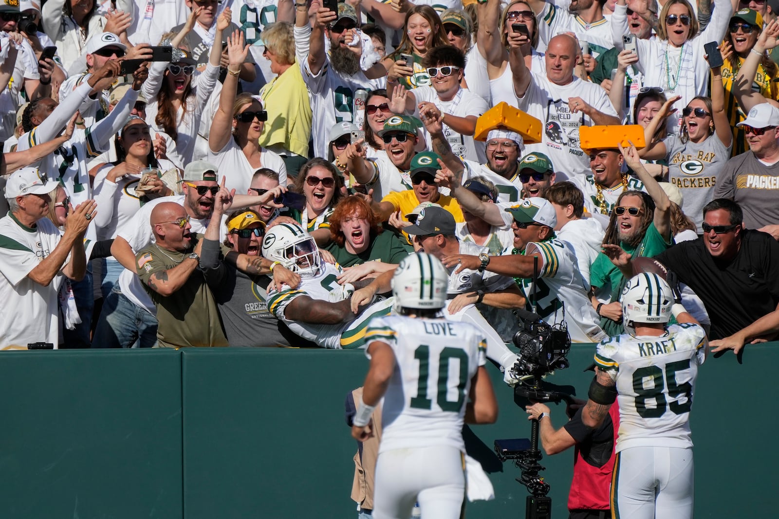 Green Bay Packers running back Josh Jacobs (8) jumps in the crowd after catching a touchdown pass during the second half of an NFL football game against the Houston Texans, Sunday, Oct. 20, 2024, in Green Bay, Wis. (AP Photo/Morry Gash)