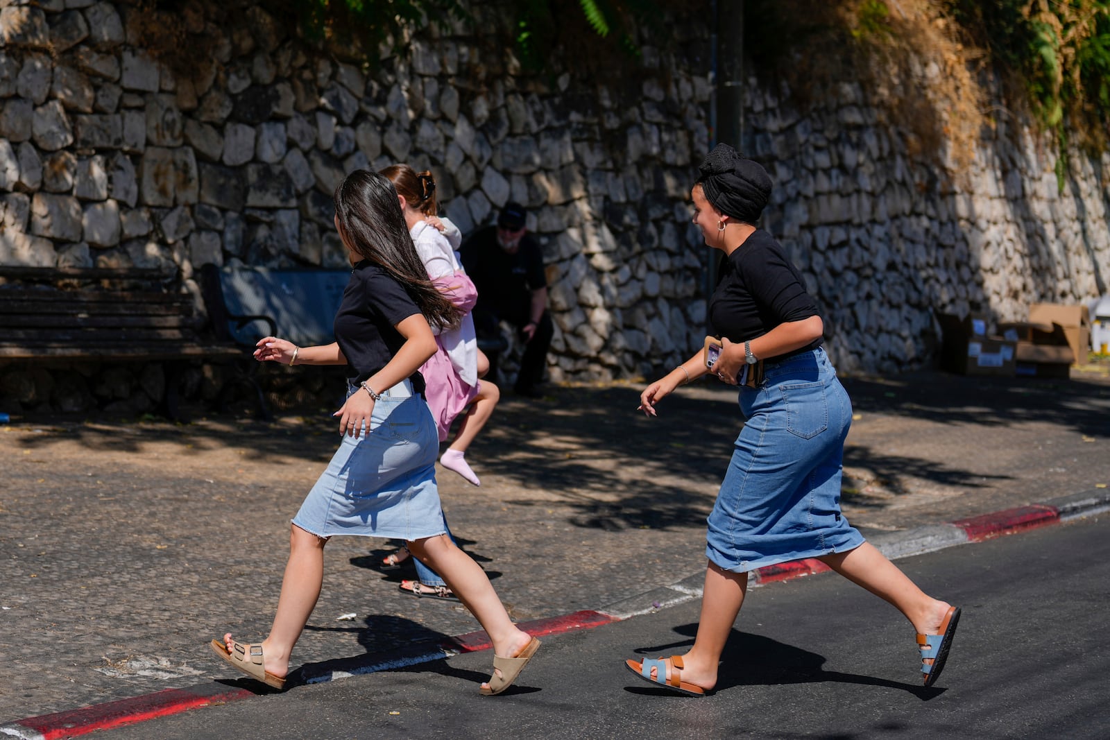 People run to take cover as a siren sounds a warning of incoming rockets fired from Lebanon, in Safed, northern Israel, Thursday, Sept. 26, 2024. (AP Photo/Ariel Schalit)