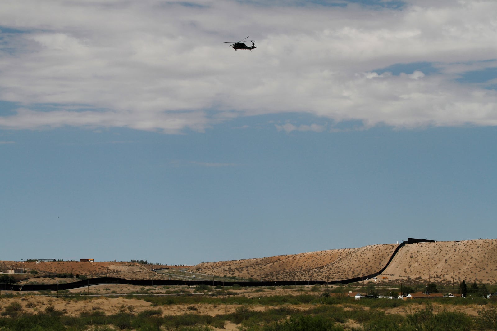 A surveillance helicopter traces a line in the sky above the Southwest border with Mexico at Sunland Park, N.M., Thursday, Aug. 22, 2024. The politics of immigration look different from communities on the Southwest border that are voting in hotly contested congressional races. (AP Photo/Morgan Lee)