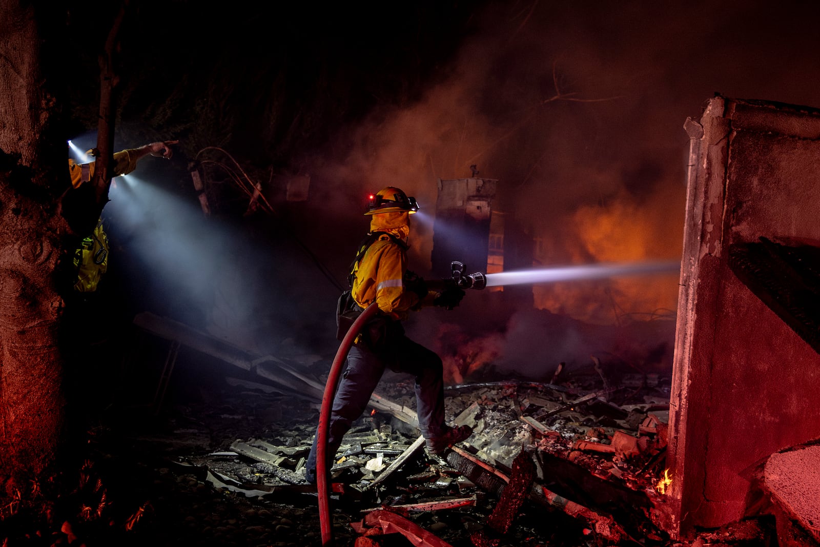 Firefighter Missy Forrett with the Beverly Hills Fire Department puts out flames at a home destroyed by the Mountain Fire in Camarillo, Calif., Wednesday, Nov. 6, 2024. (Stephen Lam/San Francisco Chronicle via AP)