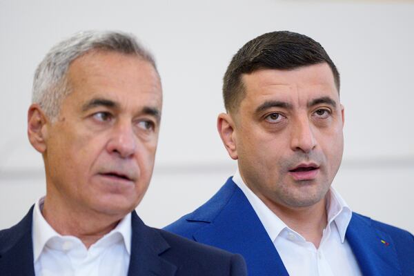 Presidential candidate George Simion, right, and Calin Georgescu, winner of the first round of last year's annulled election, speak to the media after casting their votes in the second round of the country's presidential election redo in Mogosoaia, Romania, Sunday, May 18, 2025. (AP Photo/Andreea Alexandru)
