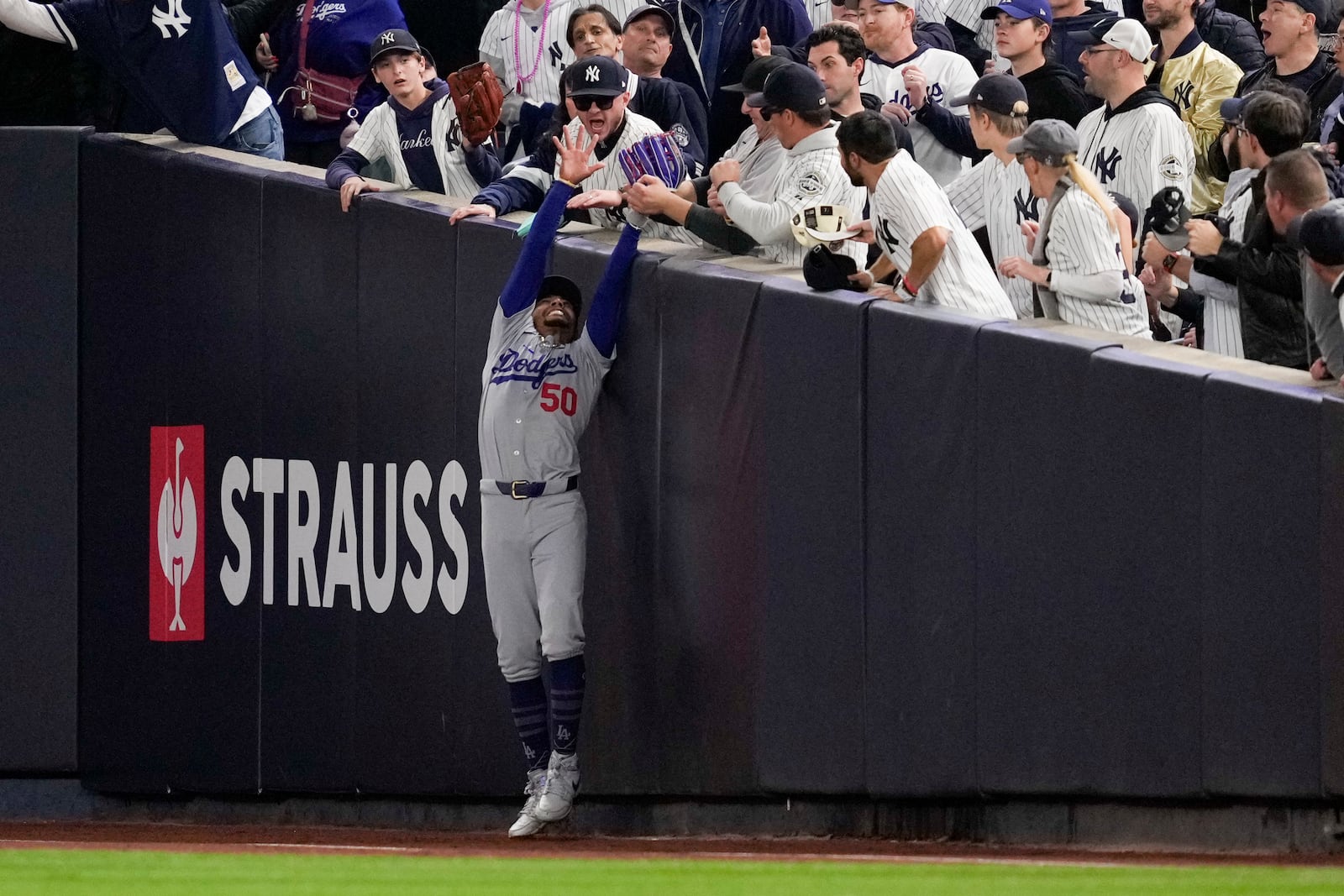 Fans interfere with a foul ball caught by Los Angeles Dodgers right fielder Mookie Betts during the first inning in Game 4 of the baseball World Series against the New York Yankees, Tuesday, Oct. 29, 2024, in New York. (AP Photo/Ashley Landis)