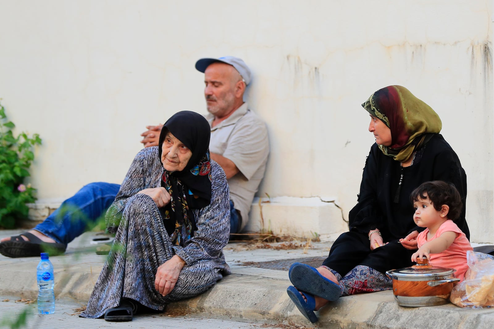 People fleeing the southern villages amid ongoing Israeli airstrikes, sit on the sidewalk outside a school in Sidon, Monday, Sept. 23, 2024. (AP Photo/Mohammed Zaatari)