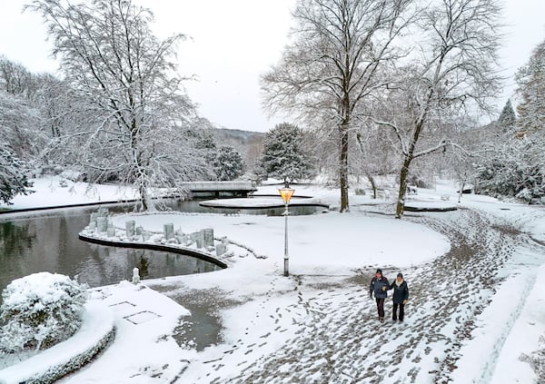 People walk through a park covered in snow after the overnight snowfall in Buxton, Derbyshire, Britain, Tuesday Nov. 19, 2024. (Peter Byrne/PA via AP)