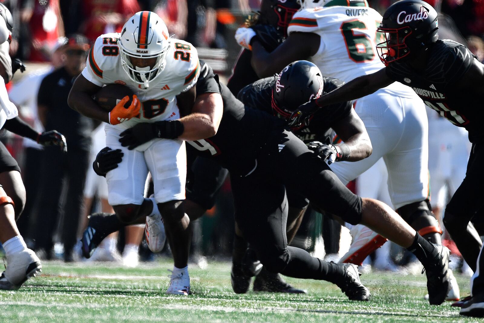 Miami running back Ajay Allen (28) is tackled by Louisville defensive lineman Ashton Gillotte (9) during the second half of an NCAA college football game in Louisville, Ky., Saturday, Oct. 19, 2024. Miami won 52-45. (AP Photo/Timothy D. Easley)