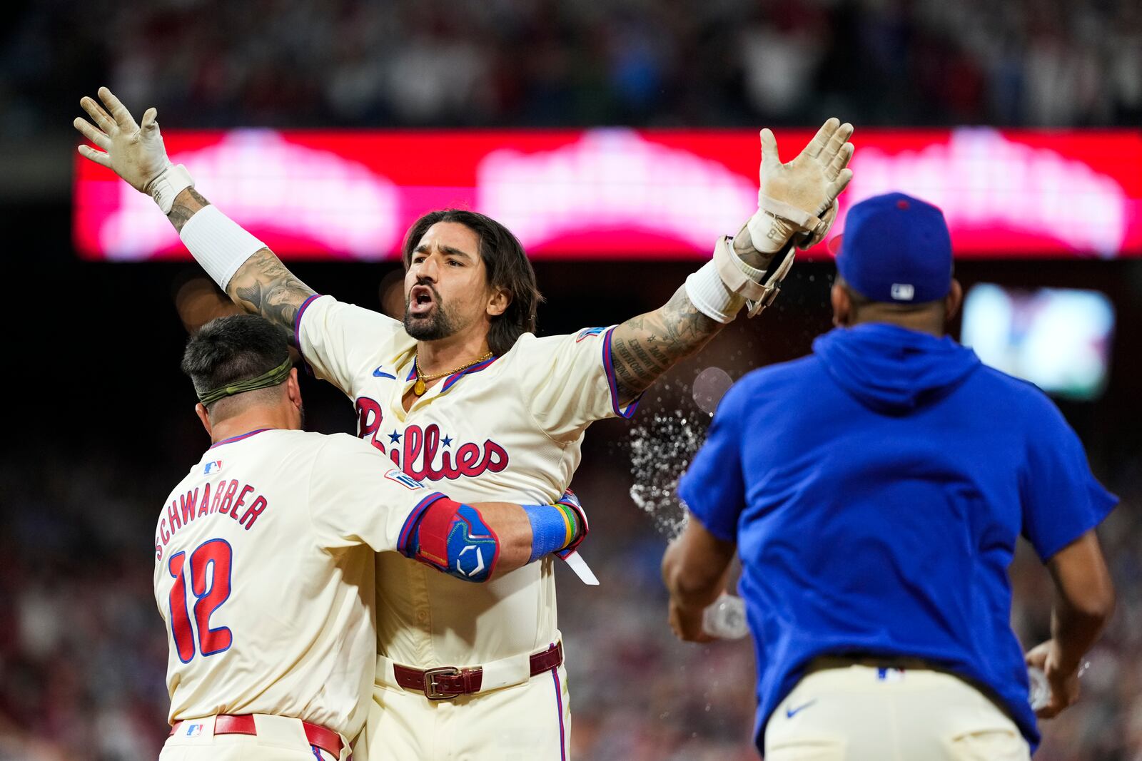 Philadelphia Phillies' Nick Castellanos celebrates with Kyle Schwarber and teammates his one-run single against New York Mets pitcher Tylor Megill during the ninth inning to win Game 2 of a baseball NL Division Series, Sunday, Oct. 6, 2024, in Philadelphia. (AP Photo/Matt Slocum)