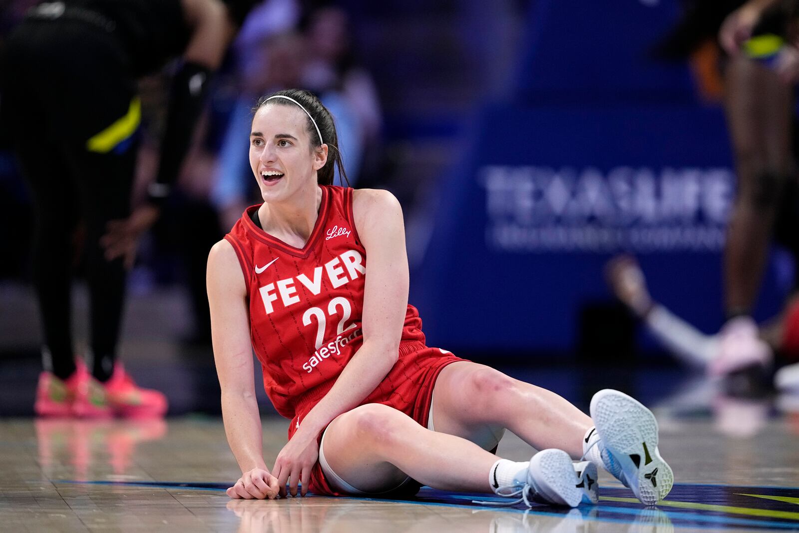 Indiana Fever guard Caitlin Clark smiles as she looks to the team bench after making a pass to the basket that lead to a score in the second half of a WNBA basketball game against the Dallas Wings Sunday, Sept. 1, 2024, in Arlington, Texas. (AP Photo/Tony Gutierrez)