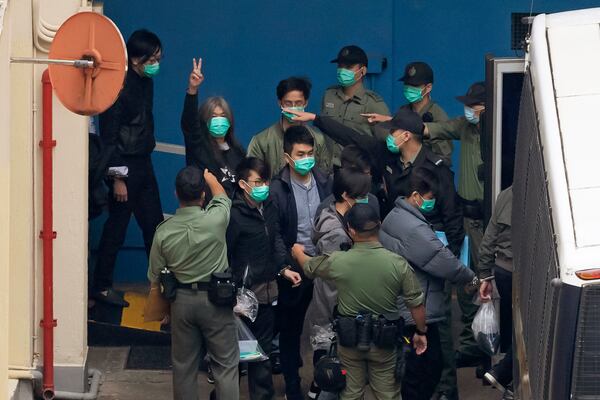 FILE - Former lawmaker Leung Kwok-hung, known as "Long Hair," second left, shows a victory sign as some of the 47 pro-democracy activists are escorted by Correctional Services officers to a prison van in Hong Kong, March 4, 2021. (AP Photo/Kin Cheung, File)