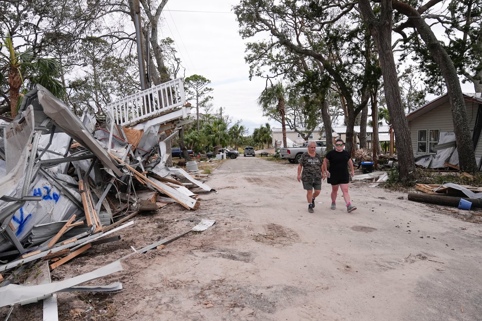 Charlene Huggins, and her daughter-in-law, Katelyn Huggins, right, walk past the destruction on their street in the aftermath of Hurricane Helene, in Horseshoe Beach, Fla., Saturday, Sept. 28, 2024. (AP Photo/Gerald Herbert)