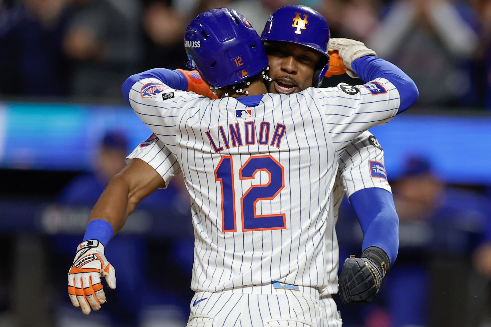 New York Mets' Francisco Lindor (12) hugs Starling Marte (6) after hitting a grand slam home run against the Philadelphia Phillies during the sixth inning of Game 4 of the National League baseball playoff series, Wednesday, Oct. 9, 2024, in New York. (AP Photo/Adam Hunger)