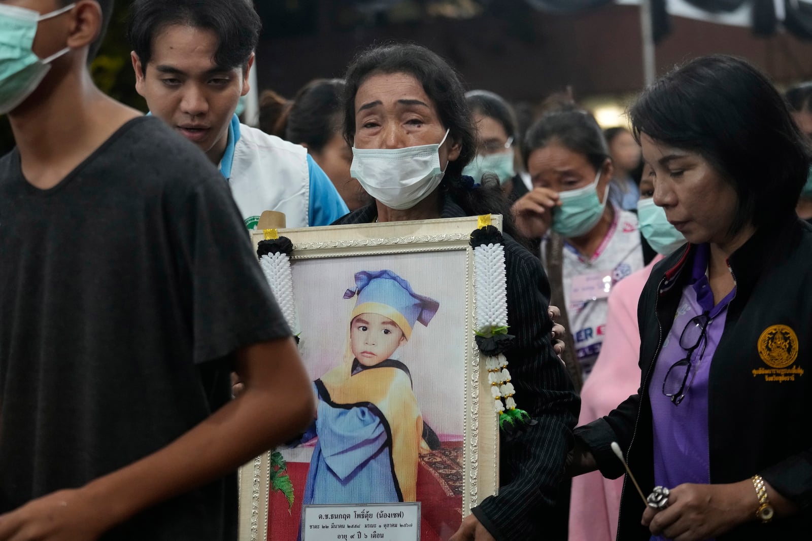 Relatives of victims in a bus fire carry portraits of the deceased in a procession at Wat Khao Phraya Sangkharam School Lan Sak , Uthai Thani province, Thailand, Thursday, Oct. 3, 2024. (AP Photo/Sakchai Lalit)