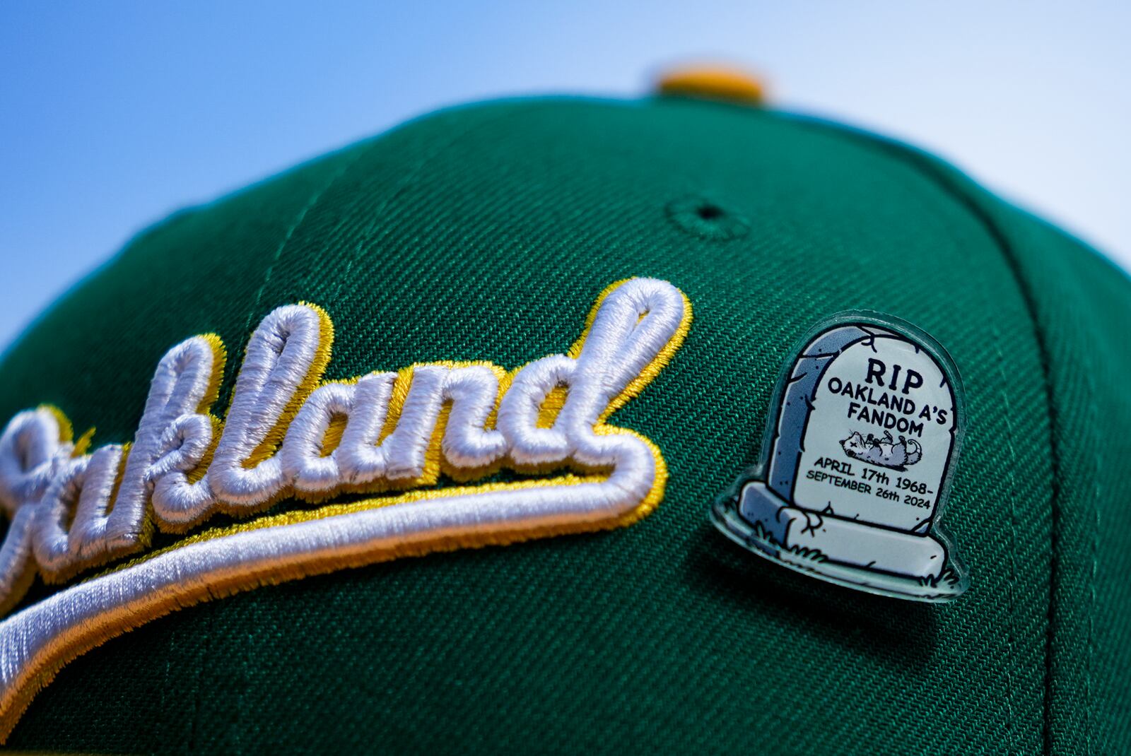 A fan wears an Oakland Athletics hat with a pin referencing the end of the team's time in Oakland before a baseball game against the Seattle Mariners, Sunday, Sept. 29, 2024, in Seattle. (AP Photo/Lindsey Wasson)