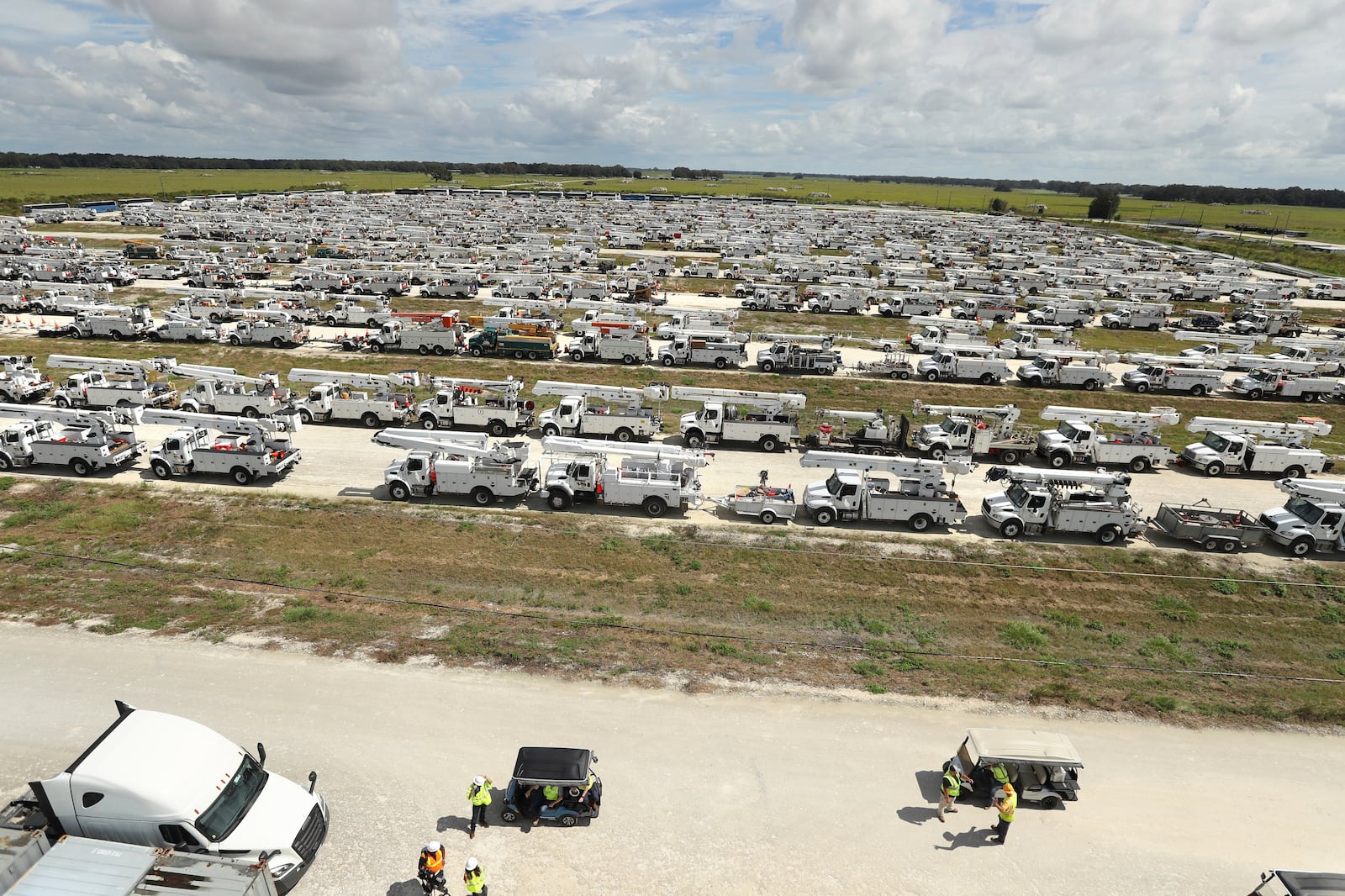 Linemen gather in front of hundreds of utility trucks staged, Tuesday, Oct. 8, 2024. at The Villages, Fla. in preparation for Hurricane Milton.(Stephen M. Dowell/Orlando Sentinel via AP)