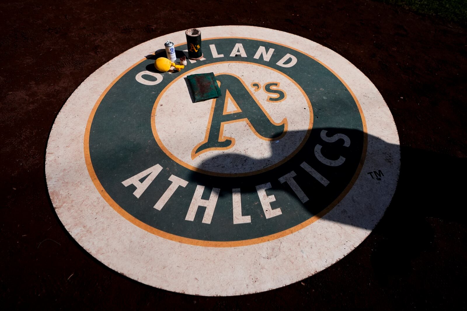 A person casts a shadow on the Oakland Athletics on-deck circle before a baseball game against the Seattle Mariners, Sunday, Sept. 29, 2024, in Seattle. (AP Photo/Lindsey Wasson)