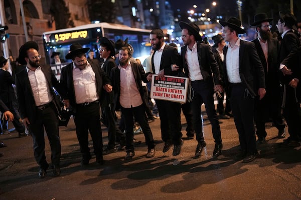 Ultra-Orthodox Jewish men block a road during a protest against army recruitment in Bnei Brak, near Tel Aviv, Israel, Sunday, Nov. 17, 2024. (AP Photo/Francisco Seco)