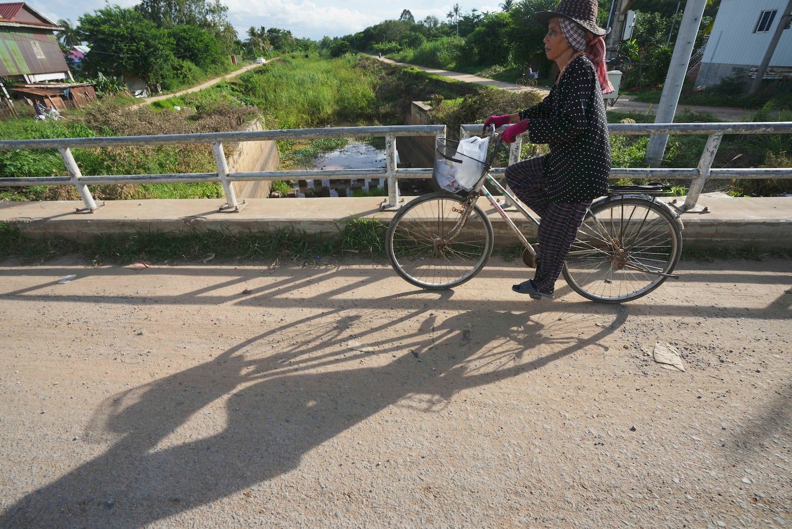 A villager who lives along the Funan Techo Canal rides a bicycle past a bridge at Prek Takeo village, eastern Phnom Penh Cambodia, Tuesday, July 30, 2024. (AP Photo/Heng Sinith)