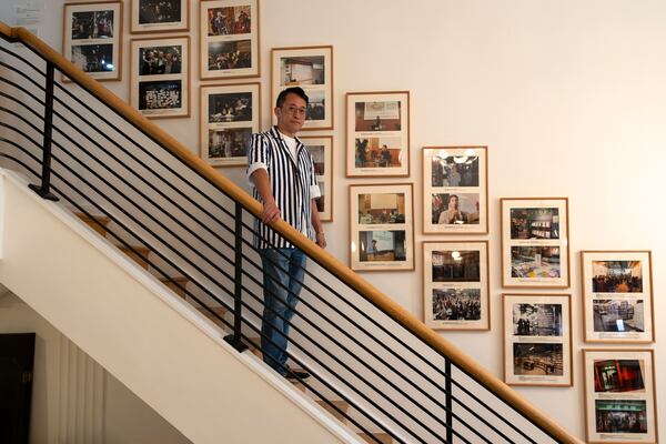 Yu Miao, owner of JF Books, poses by a wall of photographs showing his previous bookstore in Shanghai, at his bookstore in Washington, Thursday, Oct. 3, 2024. (AP Photo/Ben Curtis)