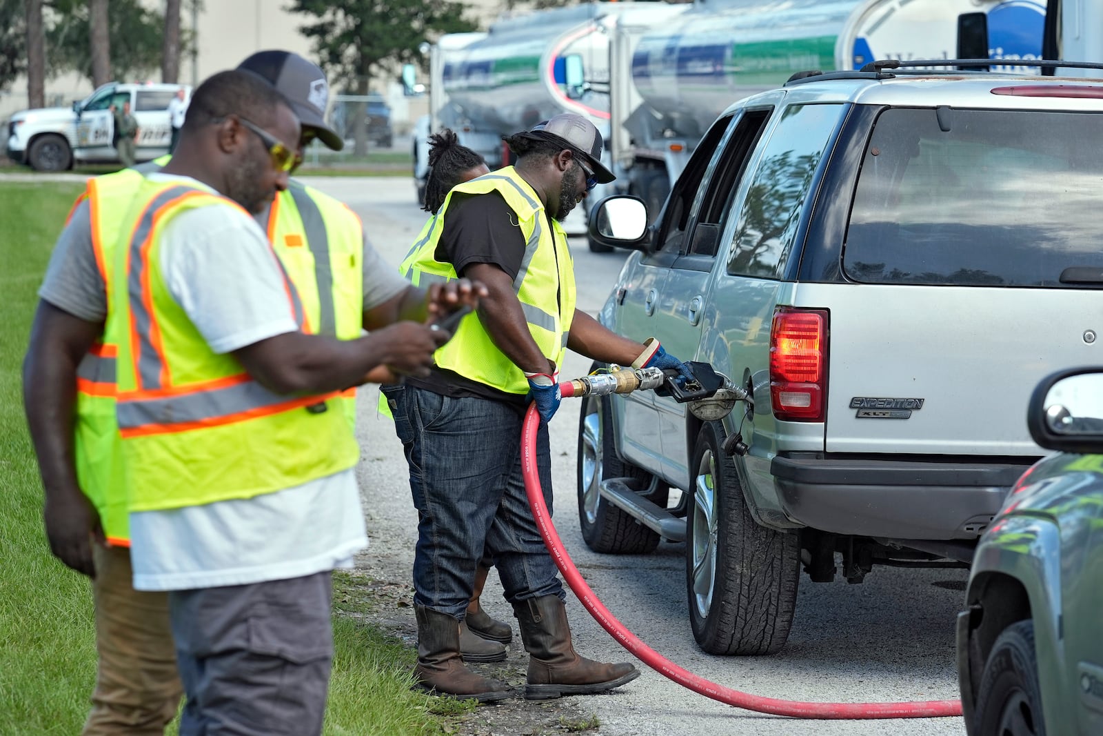 Fuel distribution workers fill cars at a depot, Saturday, Oct. 12, 2024, in Plant City, Fla. Gas stations are slow to reopen after the effects of Hurricane Milton. (AP Photo/Chris O'Meara)