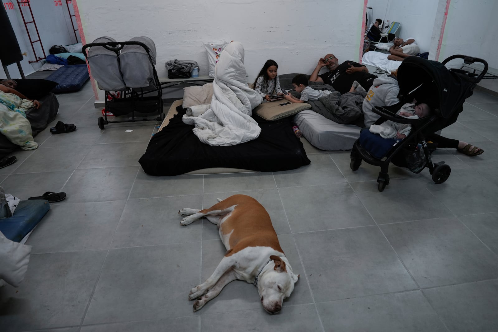 Israelis stay in a residential building bomb shelter to stay safe from rockets fired from Lebanon, in Kiryat Haim, northern Israel, on Tuesday, Sept. 24, 2024. (AP Photo/Baz Ratner)