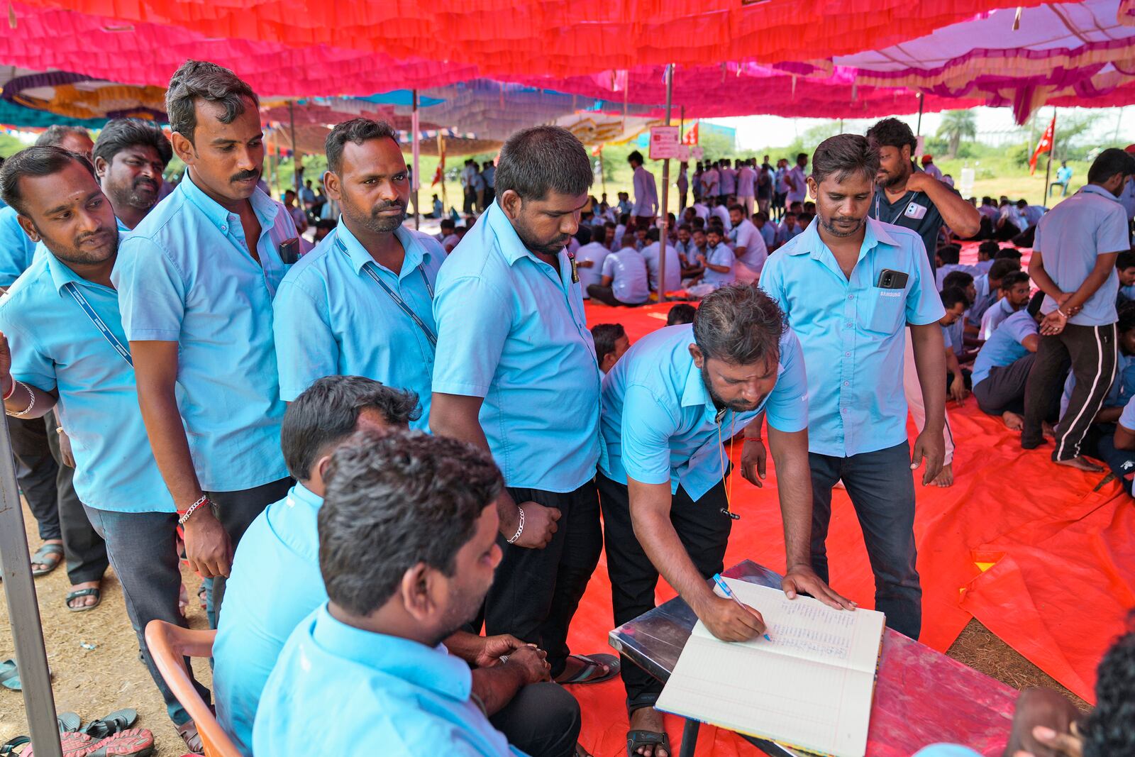 Samsung workers who are on strike sign a register as they arrive for a protest near their plant in Sriperumbudur, on the outskirts of Chennai, India, Tuesday, Sept. 24, 2024. (AP Photo/Mahesh Kumar A.)