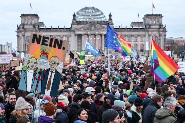 FILE - A protester holds a sign with a painted picture of Alice Weidel (AfD) and Friedrich Merz (CDU) with a burning Reichstag building and the inscription "No" during a demonstration in front of the Reichstag building in Berlin, Feb. 2, 2025. (Hannes P. Albert/dpa via AP)