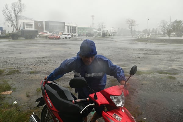 A man pushes his motorbike during heavy rains caused by Typhoon Usagi at Santa Ana, Cagayan province, northern Philippines on Thursday, Nov. 14, 2024. (AP Photo/Noel Celis)