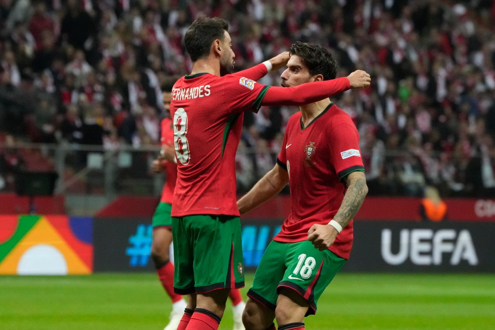 Portugal's Bruno Fernandes, left, is congratulated after assisting Bernardo Silva for his side's opening goal during the UEFA Nations League soccer match between Poland and Portugal at Narodowy stadium in Warsaw, Poland, Saturday, Oct. 12, 2024. (AP Photo/Czarek Sokolowski)