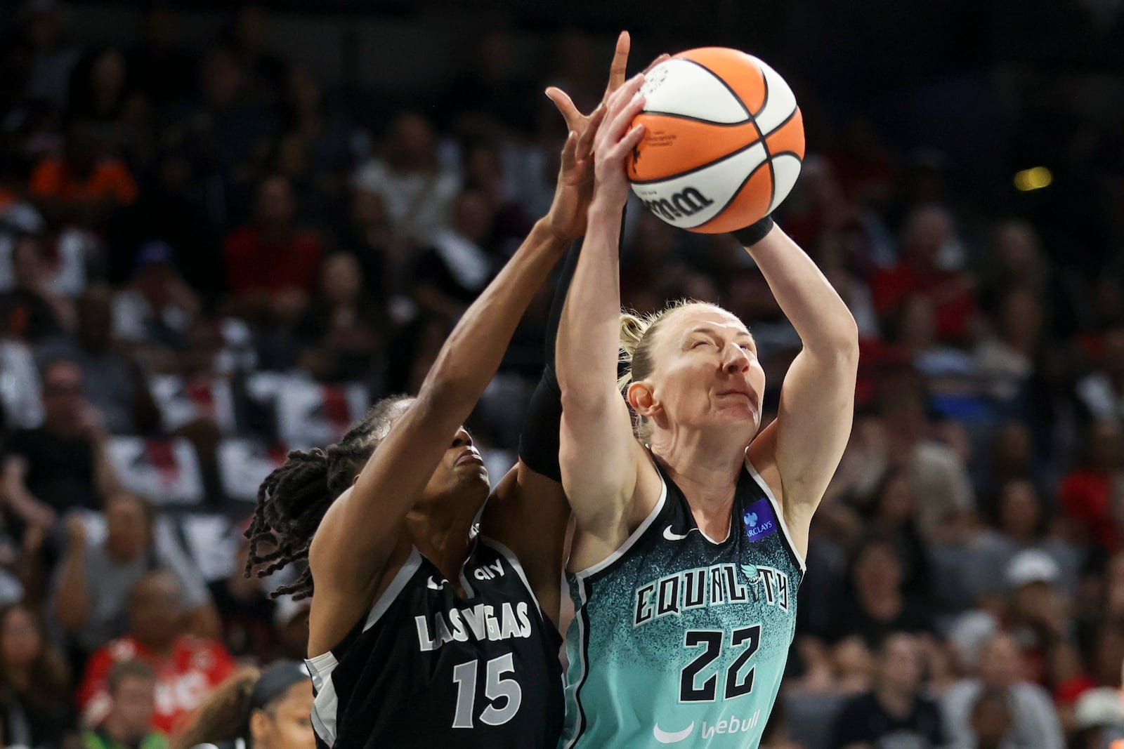 New York Liberty guard Courtney Vandersloot (22) grabs a rebound over Las Vegas Aces guard Tiffany Hayes (15) during the first half of a WNBA Semifinal basketball game, Sunday, Oct. 6, 2024, in Las Vegas. (AP Photo/Ian Maule)