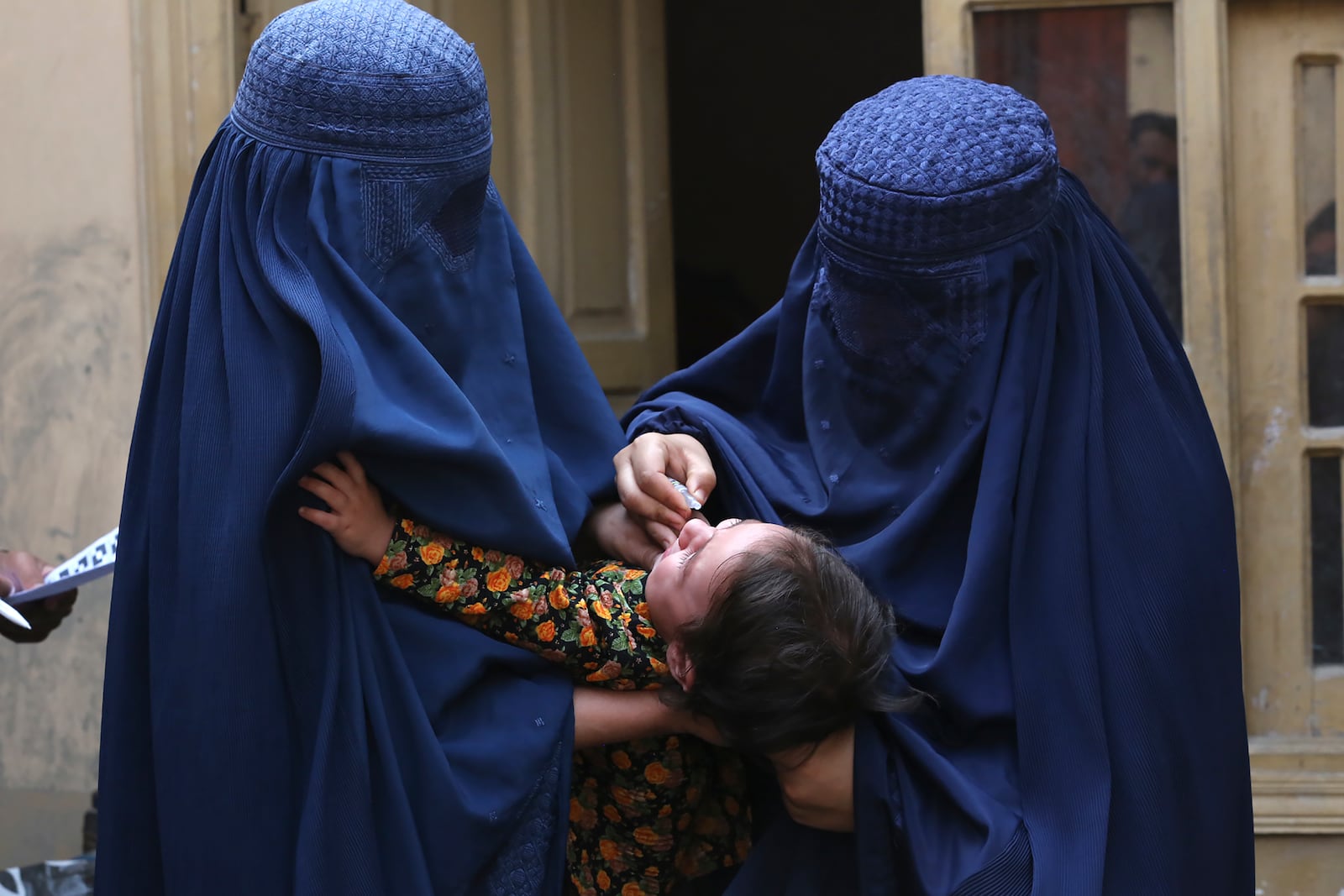 A health worker, right, administers a polio vaccine to a child at a neighborhood of Jalalabad, east of Kabul, Afghanistan, Tuesday, Oct. 29, 2024. (AP Photo/Shafiullah Kakar)