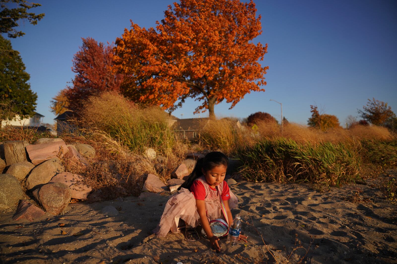 A girl from Guatemala plays in the sand on the shore of Okabena Lake in Worthington, Minn., on Sunday Oct. 20, 2024. (AP Photo/Jessie Wardarski)