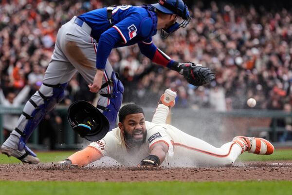San Francisco Giants' Heliot Ramos scores the game-winning run on a throwing error Texas Rangers first baseman Jake Burger during the ninth inning of a baseball game Sunday, April 27, 2025, in San Francisco. (AP Photo/Godofredo A. Vásquez)