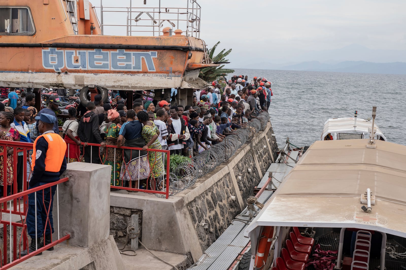 People gather at the port of Goma, Democratic Republic of Congo, after a ferry carrying hundreds capsized on arrival Thursday, Oct. 3, 2024. (AP Photo/Moses Sawasawa)