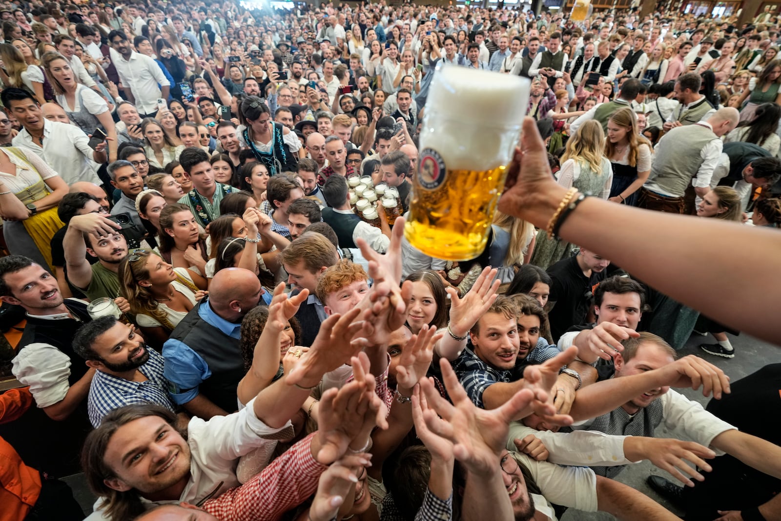 Festival goer reach out for the first glasses of beer on day one of the 189th 'Oktoberfest' beer festival in Munich, Germany, Saturday, Sept. 21, 2024. (AP Photo/Matthias Schrader)