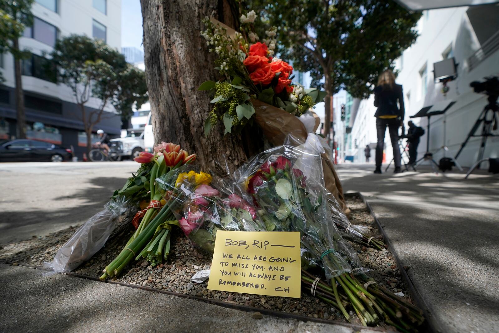 FILE - Flowers sit at a tree in front of the building where a technology executive was fatally stabbed outside of in San Francisco, April 6, 2023. (AP Photo/Jeff Chiu, File)