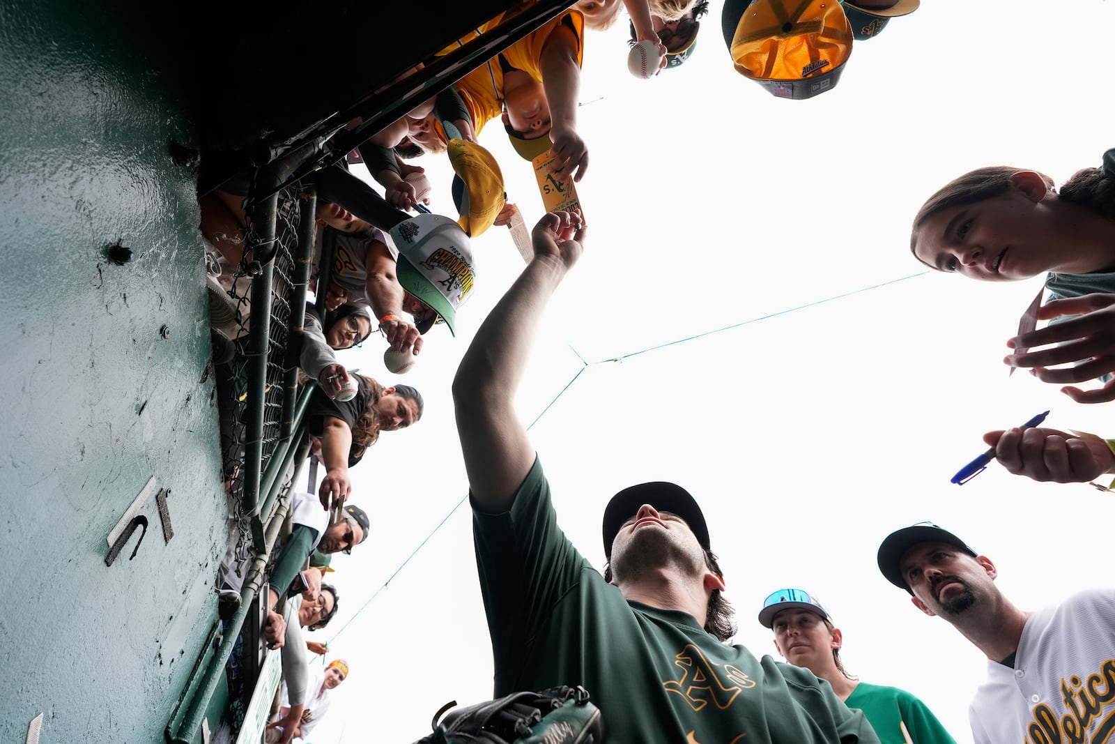 Oakland Athletics' Jacob Wilson, center, sign autographs for fans before a baseball game against the Texas Rangers, Thursday, Sept. 26, 2024, in Oakland, Calif. (AP Photo/Godofredo A. Vásquez)