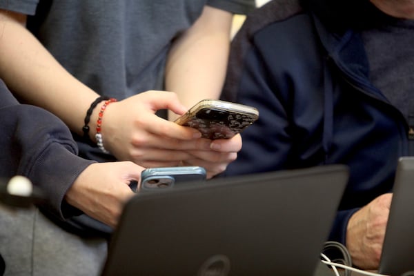 Nia McKinnon and Elizabeth Hintz, both 14, look at their phones at a charging station located in the Senior Center in Issaquah, Wash., Friday, Nov. 22, 2024. (AP Photo/Manuel Valdes)