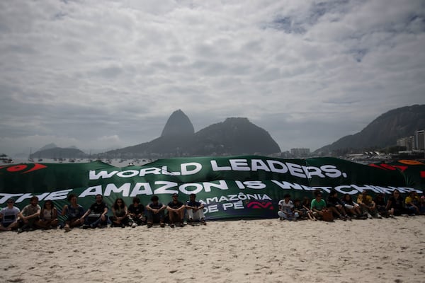 Activists from the "Amazônia de Pé" movement hold a banner with a message that reads: "World Leaders: The Amazon is watching" during a protest aimed at drawing the attention of leaders attending the upcoming G20 Summit on the Amazon Rainforest and the environmental crises, at Botafogo Beach in Rio de Janeiro, Sunday, Nov. 17, 2024. (AP Photo/Bruna Prado)