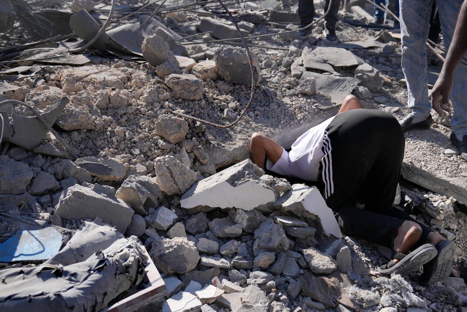 A man searches for his missing relative under the rubble of a destroyed building, at a popular neighbourhood that was hit Monday night by Israeli airstrikes, south of Beirut, Lebanon, Tuesday, Oct. 22, 2024. (AP Photo/Hussein Malla)