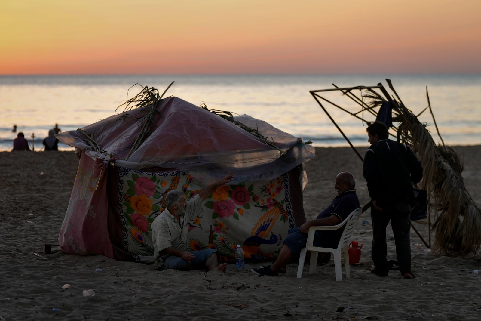 A displaced family sits next to their tent as a temporary shelter at Ramlet al-Baida public beach, after fleeing the Israeli airstrikes in the south, in Beirut, Lebanon, Tuesday, Oct. 8, 2024. (AP Photo/Bilal Hussein)