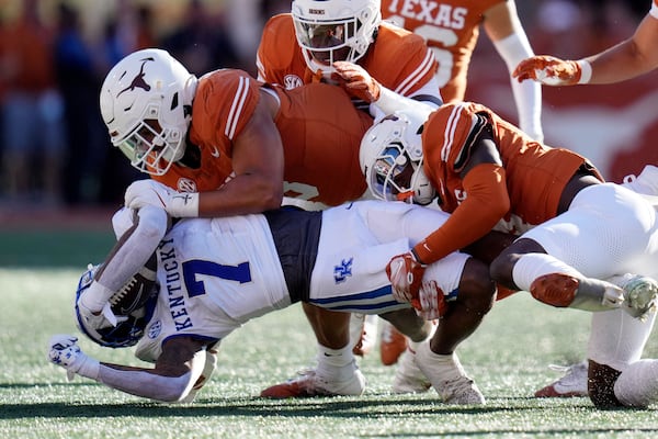 Kentucky wide receiver Barion Brown (7) is stopped by Texas defensive back Andrew Mukuba, right, and linebacker Trey Moore, left, during the first half of an NCAA college football game in Austin, Texas, Saturday, Nov. 23, 2024. (AP Photo/Eric Gay)