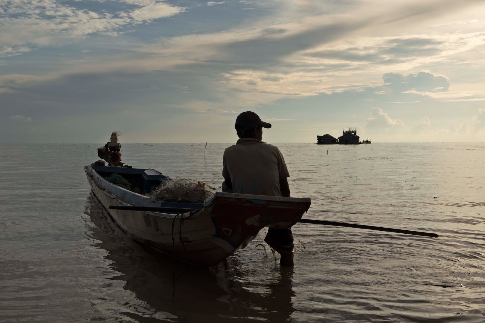 A fisherman sits on a boat in the Tonle Sap lake, Siem Reap, Cambodia, Friday, Aug. 2, 2024. (AP Photo/Aniruddha Ghosal)