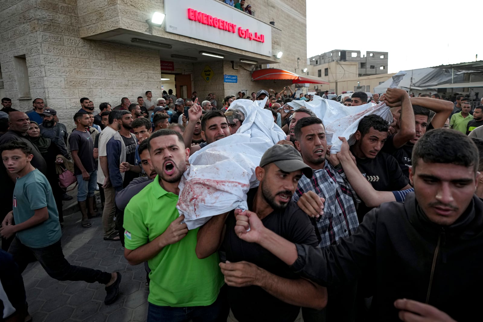 Palestinians mourn as they carry the bodies of relatives killed in the Israeli bombardment of the Gaza Strip at a hospital in Deir el-Balah, Sunday, Oct. 20, 2024. (AP Photo/Abdel Kareem Hana)