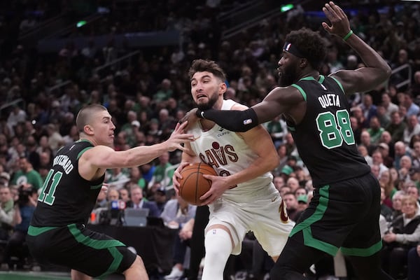 Cleveland Cavaliers guard Ty Jerome, center, tries to drive between Boston Celtics guard Payton Pritchard (11) and center Neemias Queta (88) during the first half of an Emirates NBA Cup basketball game, Tuesday, Nov. 19, 2024, in Boston. (AP Photo/Charles Krupa)