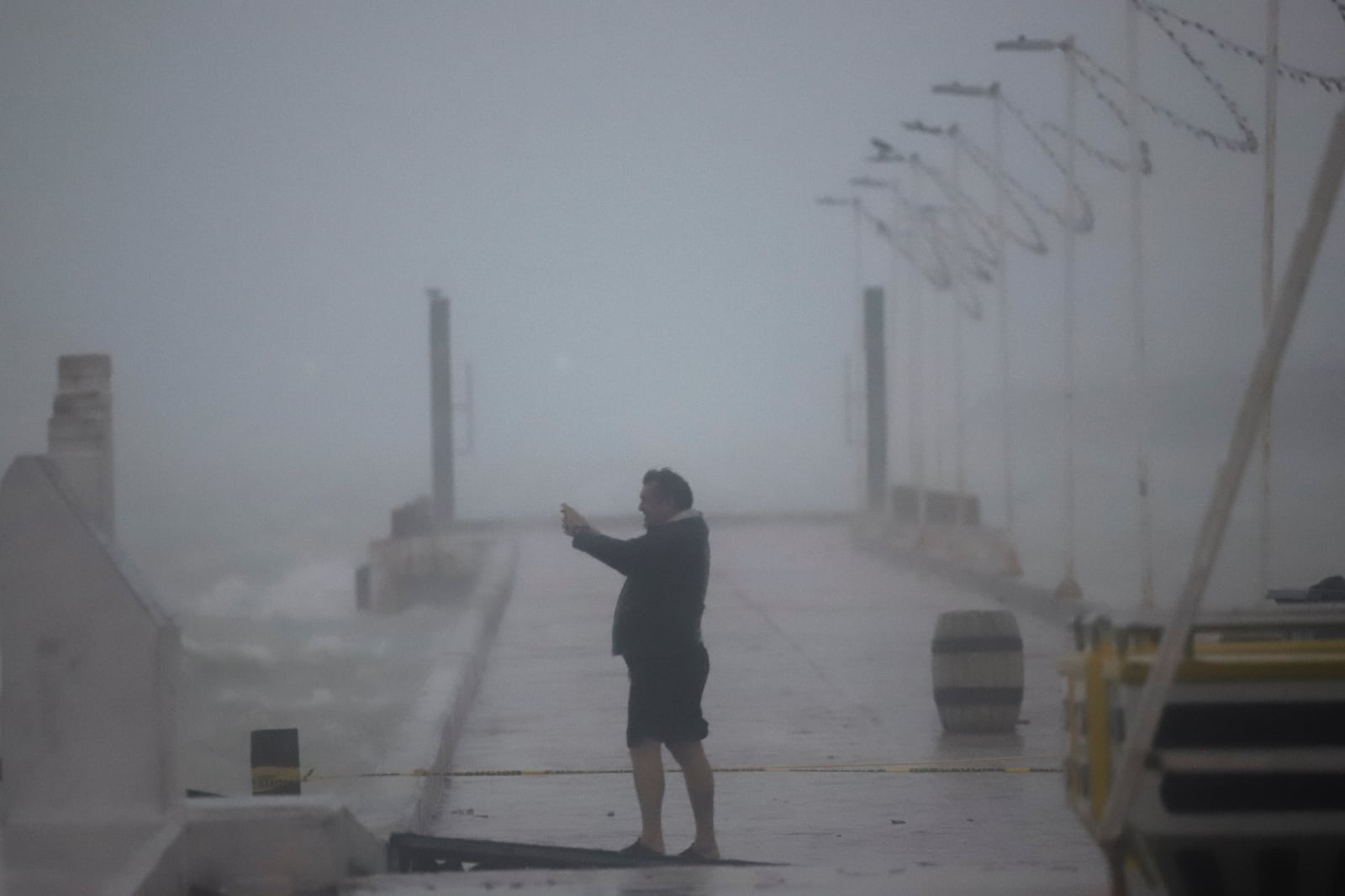 A person takes photos at the harbor amid rain as Hurricane Milton passes near Progreso, Yucatan state, Mexico, Tuesday, Oct. 8, 2024. (AP Photo/Martin Zetina)