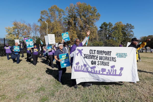 Airport workers wave signs as they march in front of the Charlotte Douglas International Airport in Charlotte, N.C., Monday, Nov. 25, 2024. (AP Photo/Nell Redmond)