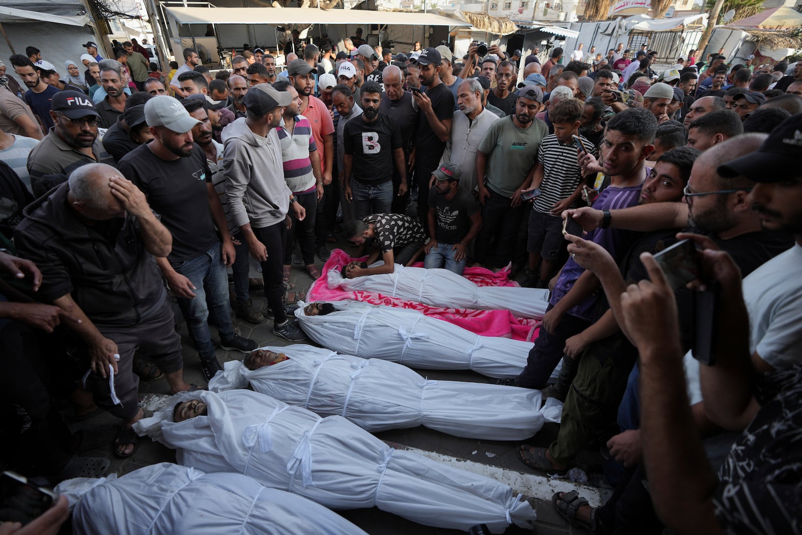 Mourners gather around the bodies of Palestinian men who were killed in an Israeli airstrike in Deir al-Balah, Gaza, Sunday, Oct. 6, 2024. (AP Photo/Abdel Kareem Hana)