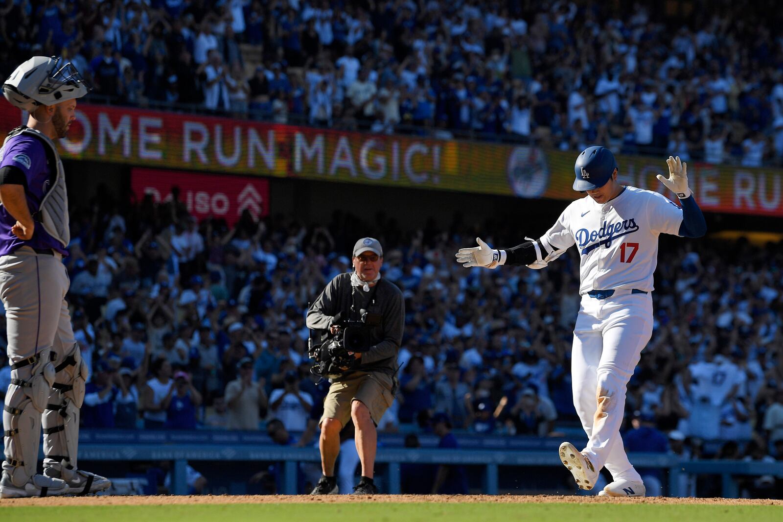 Los Angeles Dodgers' Shohei Ohtani, right, scores after hitting a solo home run as Colorado Rockies catcher Jacob Stallings stands at the plate during the ninth inning of a baseball game, Sunday, Sept. 22, 2024, in Los Angeles. (AP Photo/Mark J. Terrill)