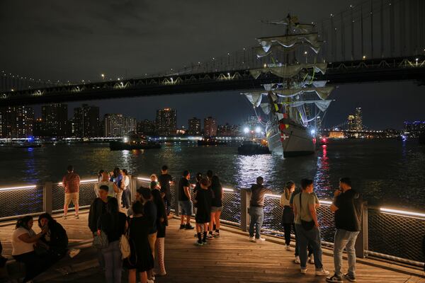 Visitors to Brooklyn Bridge Park look on as a masted Mexican Navy training ship sits stranded near the Manhattan Bridge after colliding with the Brooklyn Bridge, Saturday, May 17, 2025, in New York. (AP Photo/Yuki Iwamura)