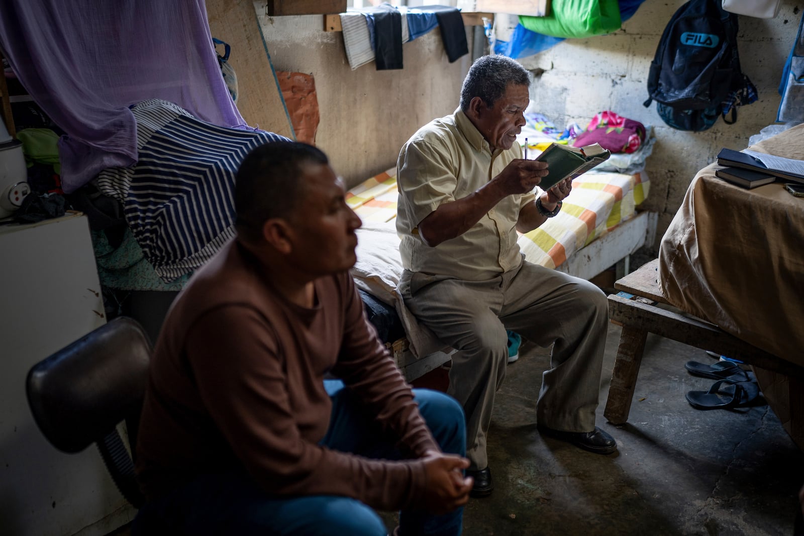 Nicaraguan exile Francisco Alvicio, right, a deacon of Nicaragua's Moravian Church, prays in his rented room in San Jose, Costa Rica, Sunday, Sept. 22, 2024. (AP Photo/Carlos Herrera)